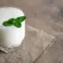 Glass of white liquid with mint leaves on a burlap cloth.