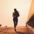 Person running on a bridge at sunset, wearing athletic clothing.