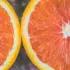 Two halves of a ripe grapefruit with vibrant pink flesh and yellow rind.