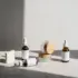 Skincare bottles and jars with wooden lids on a sunlit fabric surface.