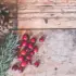 Pine cones, rosemary, and cranberries on rustic wooden surface.
