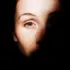Half-lit face with focus on one eye, surrounded by darkness.