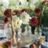 Outdoor table with vases of colourful flowers, candles, sliced cake, and fruit on a sunny day.