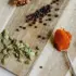 Spoons with spices and seeds on a wooden board.