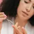 Person applying skincare serum with a dropper on their fingertip.