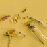 Glass vials, capsules, and yellow flowers on a yellow background.