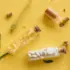 Glass vials with capsules, tablets, and powder on a yellow background with a small flower.