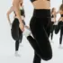 Women in black activewear stretching in a bright studio.