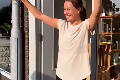 Person smiling with arms raised outside a shop. TherapyOrganics.co.uk visible on image.