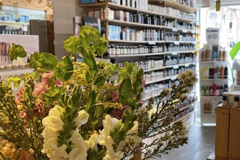 Flower arrangement in a skincare shop with shelves of products in the background.