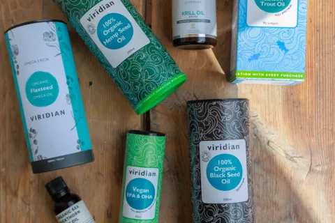 Various Viridian oil products on a wooden surface, including hemp, flaxseed, and black seed oils.