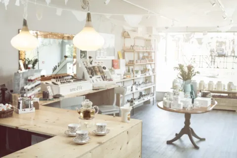 Bright skincare shop with wooden counters, shelves of products, and a table with a teapot and cups.