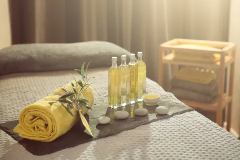 Yellow towel, oils, and stones on a massage table in a spa setting.