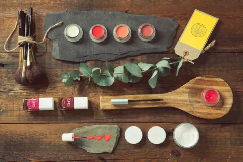 Skincare products, brushes, and eucalyptus on a wooden table.