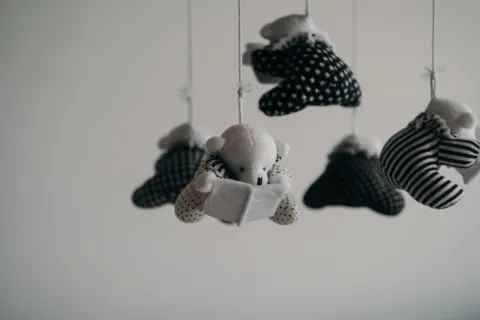 Hanging plush bears in monochrome patterns on strings against a plain background.
