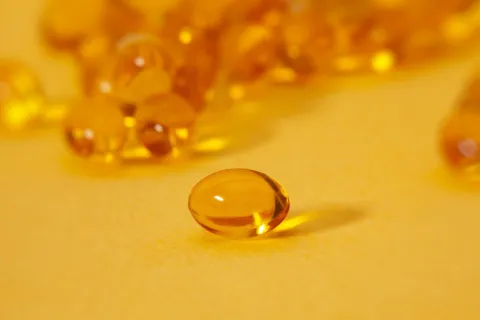 Yellow gel capsules on a yellow surface.