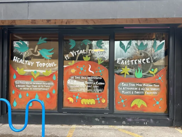 Shop window with colourful soil conservation messages and illustrations.