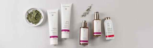 Skincare products with rosemary and green paste in a dish on a light background.