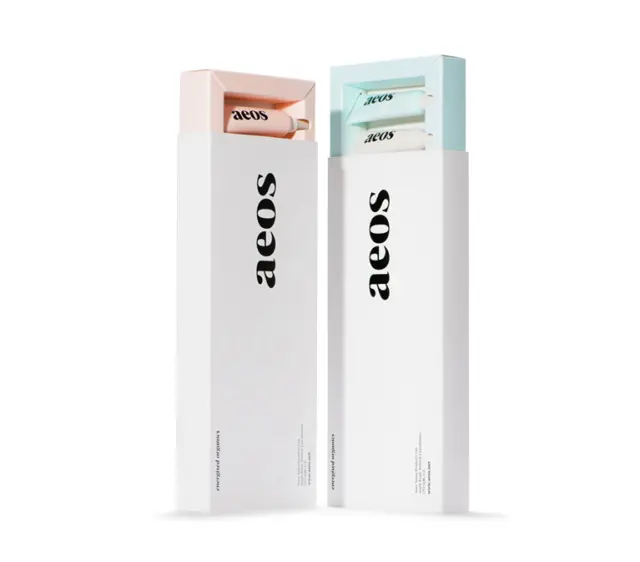 Two aeos skincare boxes, one pink, one blue, with visible product tubes inside.