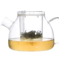 Clear glass teapot with infuser, containing green tea leaves and brewed tea.