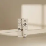 Deodorant balm tube and box with text, set against a neutral background.