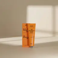 Orange deodorant balm tube and box with text "SC.01 EXT. ORANGE GROVE".