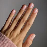 Hand with neatly manicured nails, wearing a pink knitted sleeve.