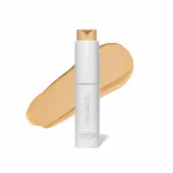White bottle of RMS Beauty foundation with beige swatch behind.