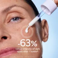 Dropper applying serum to woman's cheek, text: "-63% colour intensity of dark spots after 1 bottle".