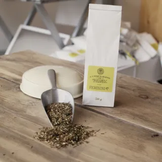 Herbal tea blend labelled "FEMININI-T" with a scoop on a wooden table.