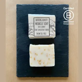 Two bars of oat and honey soap on a slate, labelled for sensitive skin. Certified B Corporation logo.
