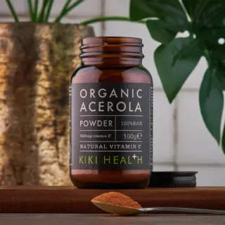 Brown jar of organic acerola powder, 100g, with a spoonful of powder in front.