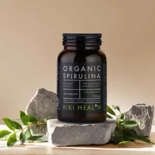 Organic Spirulina tablets by Kiki Health, 200 count, on stone with green leaves.