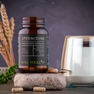Spermidine wheatgerm extract bottle with capsules, glass of milk, and wheat stalks.