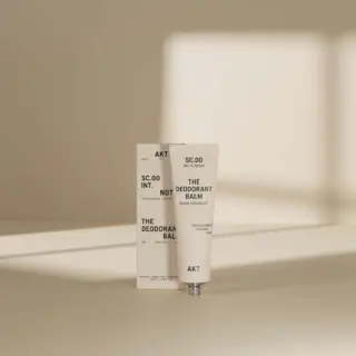 Deodorant balm tube and box with text, set against a neutral background.