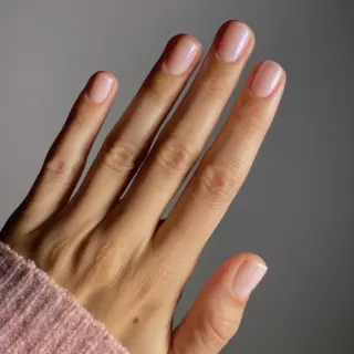Hand with neatly manicured nails, wearing a pink knitted sleeve.