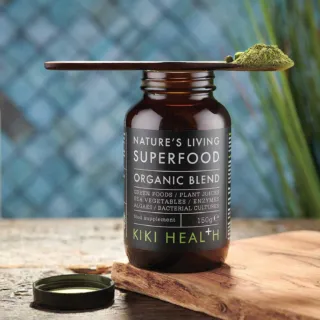 Brown bottle labelled "Nature's Living Superfood Organic Blend" with green powder on a spoon.