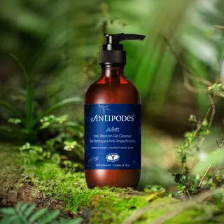 Antipodes Juliet Anti-Blemish Gel Cleanser bottle on a mossy surface with green foliage background.