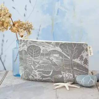 Grey pouch with landscape design, dried flowers in vase, stones, and starfish on wooden surface.