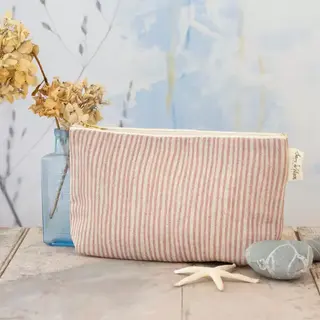 Striped fabric pouch on wooden table with dried flowers and stones.
