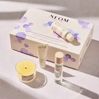 Neom Perfect Night's Sleep set with candle, cream, and spray on a light surface.