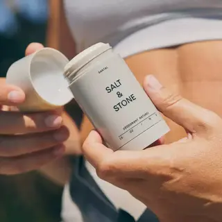 Person holding Salt & Stone deodorant stick with cap off.