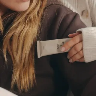 Person holding a tube labelled "Salt & Vine" against a brown jumper.