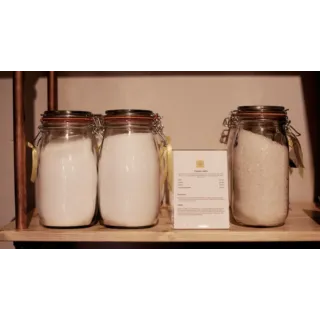 Three jars of Epsom salts on a wooden shelf with a product description card.