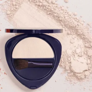 Compact with white powder and brush, surrounded by loose powder.