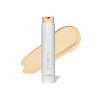White bottle of RMS Beauty foundation with beige swatch behind.