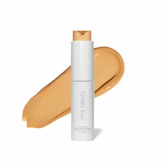 White bottle of RMS Beauty foundation with beige swatch behind.