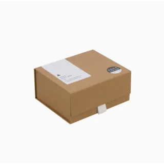 Brown gift box with white label and round black sticker on the lid.