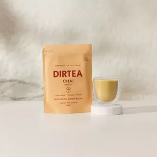 DIRTEA Chai organic mushroom blend pouch and glass cup on a white surface.