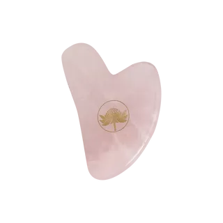 Pink heart-shaped gua sha tool with a gold floral logo.